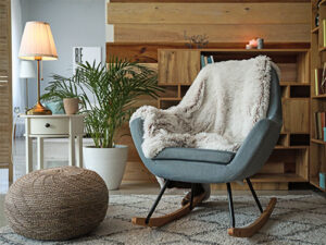 Eine gemütliche Wohnzimmer-Ecke mit einem modernen Schaukelstuhl, der mit einer flauschigen weißen Decke bedeckt ist.