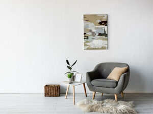 Ein minimalistisches Wohnzimmer mit einem grauen Sessel, einem beigen Kissen und einem kleinen weißen Beistelltisch.
