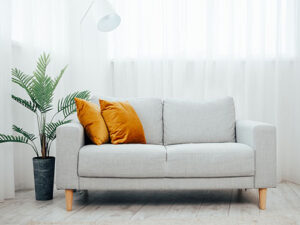 Modernes Wohnzimmer mit einem hellgrauen Sofa und zwei leuchtend orangefarbenen Kissen.