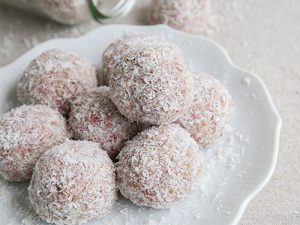 Hausgemachter Bliss Ball mit Erdbeeren, Datteln, Cashewkernen und Kokosnuss auf Vintage-Geschirr.